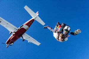 Tandem skydivers with a plane behind them for 18 Adventure Activities In Kent guide