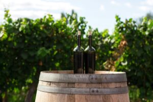 two bottles on a wooden barrel - with a vineyard in the background for Vineyard Tours & Tastings in Kent, a guide the vineyards offering experiences of tours and tastings to the public in the Garden of England