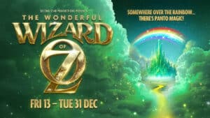 In gold to the left the Wizard of Oz and on the right in mainly green a castle in the clouds with a rainbow above it and a yellow path leading up ot the castle. For The Wonderful Wizard Of Oz at Leas Cliff Hall for pantomimes in Kent for 2024