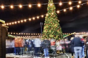 People milling around a lit Christmas tree for Christmas in Kent and events in Folkestone an the Folkestone Festive Marketplace at Folkestone Harbour