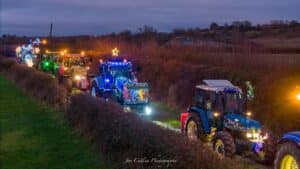 Row of tractors lit up by Christmas lights going through country lanes. for Christmas Tractor Run in and around Folkestone for Fun Festive Kent Events for Christmas
