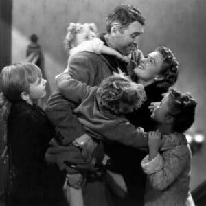 In black and white a man holding a child in his arms one on his back and a woman and two other children holding him. For It's A Wonderful Life at Folkestone Quarterhouse for Christmas in Kent and Folkestone Family festive events