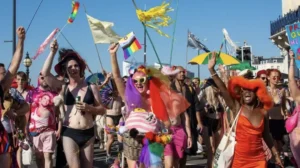 People waving flags in a parade for Margate Pride in Kent