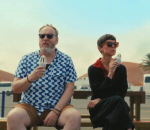 Man and a woman outside on a bench with ice creams for the poster for new film releases in Kent and Signs Of Life from Bulldog Film Distribution