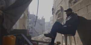 Man sitting on chair with bombed buildings behind for New film releases for cinemas in Kent and From Ground Zero from Cosmic Cat