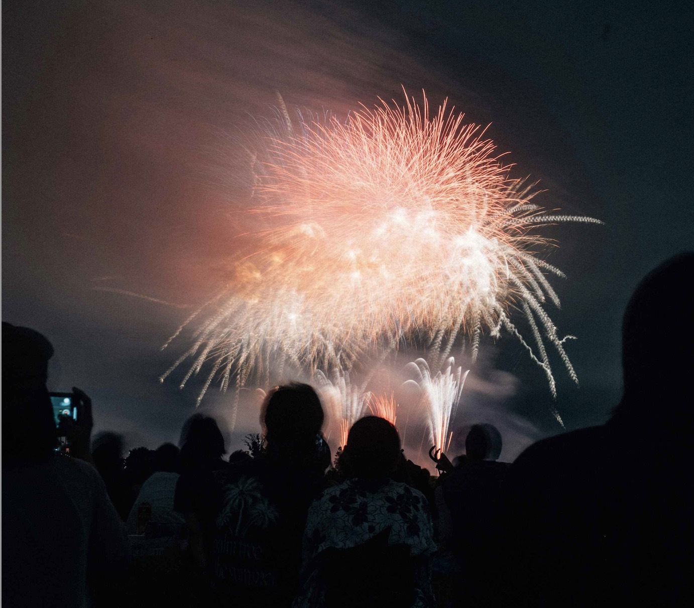 People sitting in front of a nighttime fireworks display for the guide to Fireworks for Bonfire Night & Fireworks in West Kent
