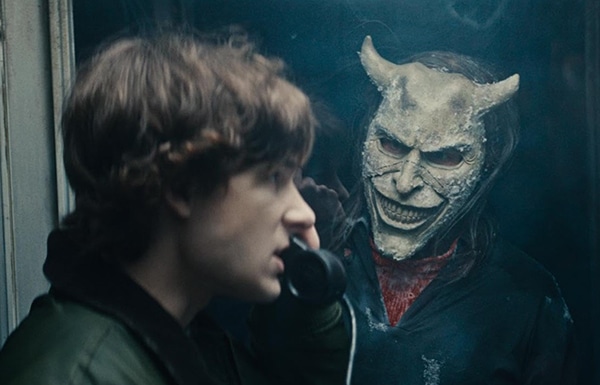 A man on a phone with a person with a mask with horns outside for new film releases for cinemas in Kent and The Black Phone 2 Universal Pictures
