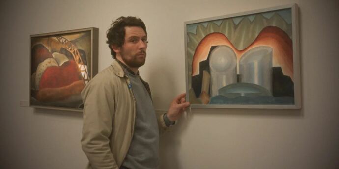 Man standing next to two pictures on a wall for New film releases for cinemas in Kent and The Mastermind from Mubi.