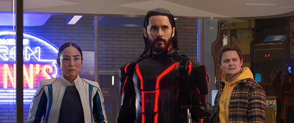 There people in a row with a lit up shop sign in the background for new film releases for cinemas in Kent and Tron: Ares from Walt Disney