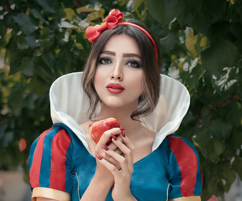 Woman dressed in costume holding a red apple for Pantomimes in Kent Guide